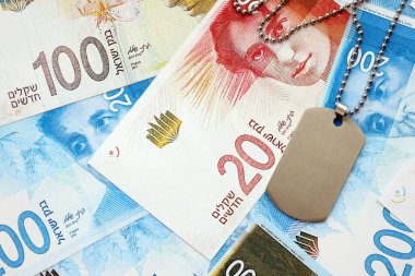 İsrail Yeni Şekelleri 'nin banknotları ve askeri simgesi. İsrail 'in mevcut para faturaları ve künyeleri büyük miktarda masada yatıyor. İsrail 'de askerlik kavramı
