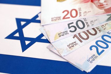 Israel New Shekels banknotları ulusal bayrak üzerinde. İsrail 'in şu anki para faturaları büyük oranda bayrağın üzerinde yatıyor. İsrail 'de iş ve yatırım kavramı