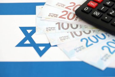 Israel New Shekels banknotları ve hesap makinesi bayrağın üzerinde. İsrail 'in mevcut para faturaları ve kalibreleri büyük oranda bayrakta yatıyor. İsrail 'de vergilendirme ve para kavramı