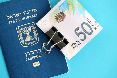 Israel New Shekels banknotları ve mavi arka planda pasaport. İsrail 'in şu anki para banknotları büyük oranda mavi üzerine yatar. İsrail 'de finans ve nakit kavramı