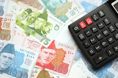 Pakistan banknotları ve hesap makinesi. Pakistan 'ın mevcut para ve hesap makinesi büyük miktarda masada yatıyor. Pakistan 'da vergi ve para sayımı kavramı