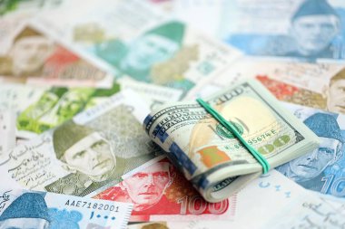 Amerikan dolarları yığını Pakistan Rupi banknotlarının büyük bir miktarına yakın duruyor. Amerikan para demeti Pakistan 'ın para banknotlarında yatıyor. Pakistan 'da ekonomi ve döviz kuru kavramı