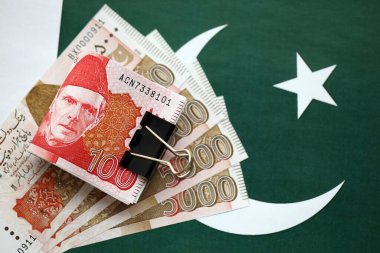 Pakistan bayrağı üzerinde Pakistan banknotları. Pakistan 'ın mevcut para faturaları büyük miktarlarda pankartta yatıyor. Pakistan 'da ekonomi ve ticaret kavramı