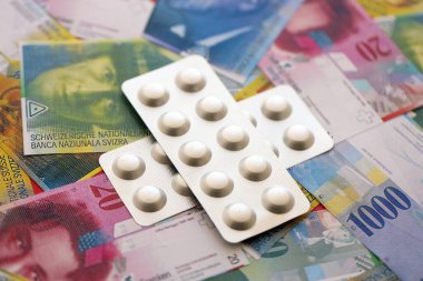 İsviçre frangı ve ilaç hapları. Mevcut para ve uyuşturucu banknotları büyük miktarda masada yatıyor. İsviçre 'de ilaç ve eczane kavramı