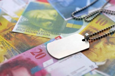 İsviçre frangı banknotları ve askeri jeton. Mevcut banknotlar ve künyeler masanın üzerinde büyük miktarda duruyor. İsviçre 'de askerlik konsepti