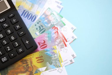 İsviçre frangı banknotları ve hesap makinesi maviye. Mevcut frank para faturaları ve calc büyük miktarda masada yatıyor. İsviçre 'de vergilendirme ve para konsepti