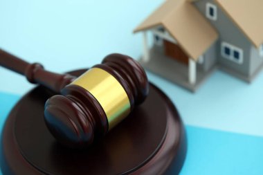 Generic toy house and judgement mallet on blue background close up