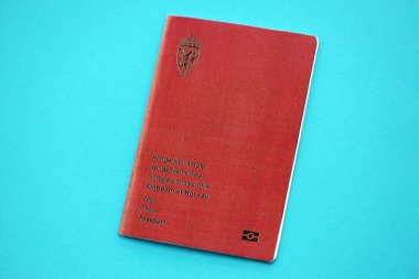 Norwegian passport book on light blue paper background close up. Travel document on blue surface