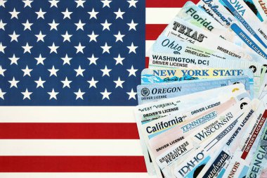 Big amount of driving licenses from different USA states on flag close up. Stack of driving license specimen cards