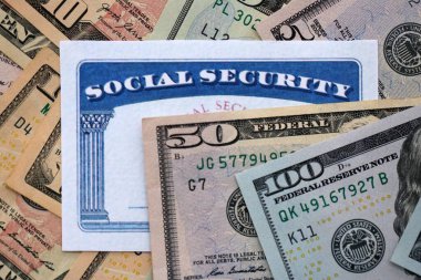 Social security number card on many US dollar money bills close up