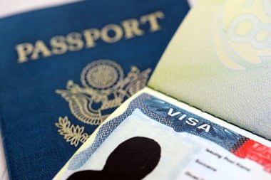 Açık pasaport sayfasında ABD vizesi ve arka planda ABD pasaport kapağı