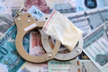 Mısır para birimi banknotları ve kelepçeli kokain paketi. Uyuşturucu suçları kavramı
