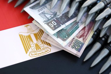 Mısır para birimi banknotları ve bayraklar üzerinde tüfek mermileri. Savaş ve silah satışı kavramı