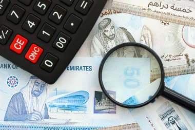 Birleşik Arap Emirlikleri kara para birimi faturaları ve büyüteçle yakınlaştırılmış hesap makinesi. Vergilendirme ve para sayımı kavramı