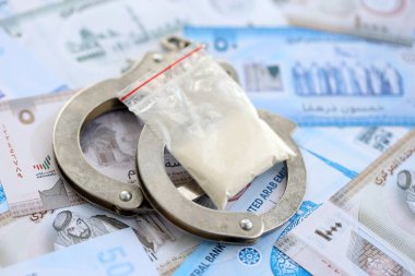 Birleşik Arap Emirlikleri kara para birimi faturaları ve kelepçeli kokain paketleri. Uyuşturucu suçları kavramı