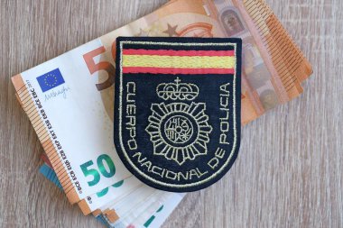 KYIV, UKRAINE - SEPTEMBER 6, 2025 Spain National Police Corps patch on big amount of euro money banknotes on table close up