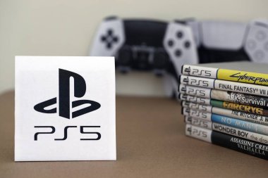 KYIV, UKRAINE - 17 Eylül 2025 PS5 video oyun diski kutuları ve modern dualsense kenar oyun sahası. Ön tarafta PS5 logosu var.