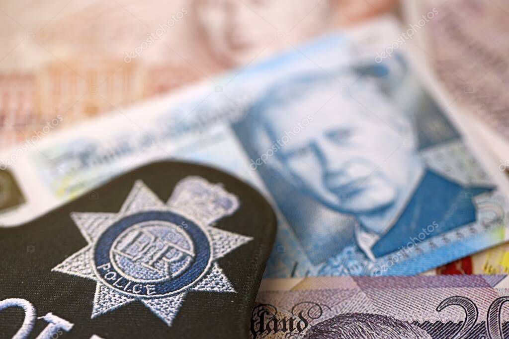 KYIV, UKRAINE - SEPTEMBER 17, 2025 United Kingdom Police badge on British pound money bills close up
