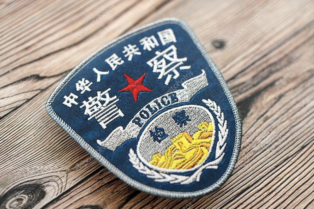 KYIV, UKRAINE - SEPTEMBER 17, 2025 Chinese Police badge on brown wooden table surface close up