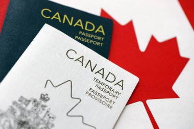Canadian temporary and permanent passports lies on flag close up
