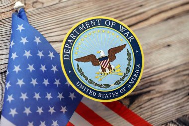 KYIV, UKRAINE - 17 Eylül 2025 ABD Savaş Bakanlığı rozeti ve ahşap masa üzerinde bayrak