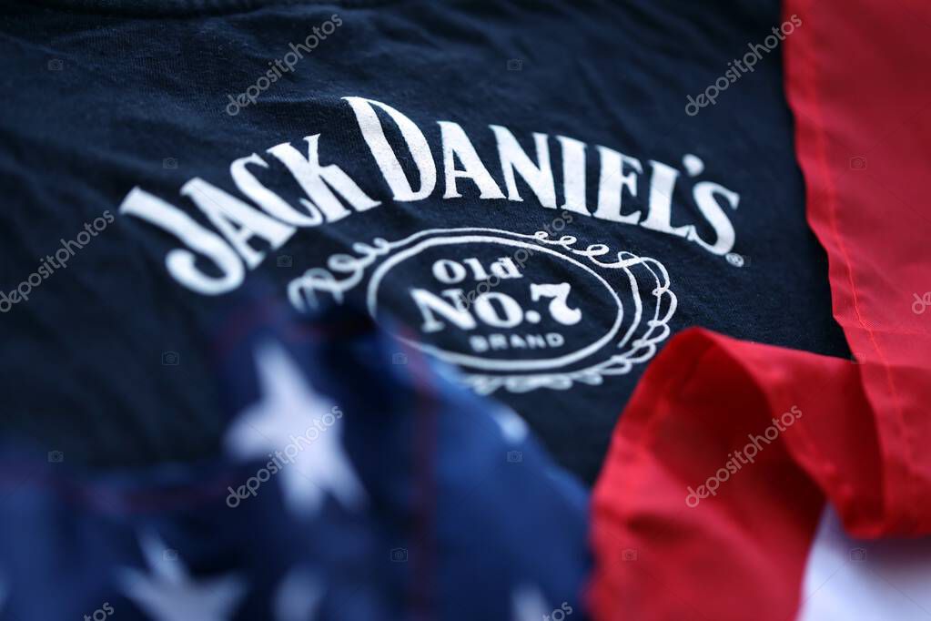 KYIV, UKRAINE - AUGUST 31, 2025 Jack Daniels Tennessee sour mash Whiskey logotype on fabric with US flag close up