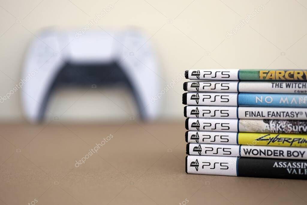 KYIV, UKRAINE - SEPTEMBER 17, 2025 Stack of PS5 videogame disc boxes and modern dualsense edge gamepad closer up