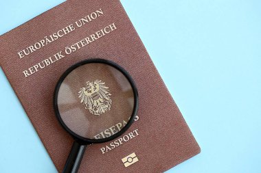 Avusturya pasaportu ve açık mavi kağıtta büyüteç yakın plan. Vatandaşlık detayları ve bilgi kavramı