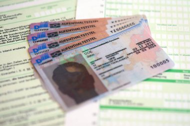 German Permanent resident specimen cards lies on german tax form close up. Aufenthaltstitel and einkommensteuererklarung