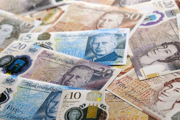 КИЕВ, УКРАИНА - 17 СЕНТЯБРЯ 2025 г. Большое количество банкнот в фунтах стерлингов на столе крупным планом