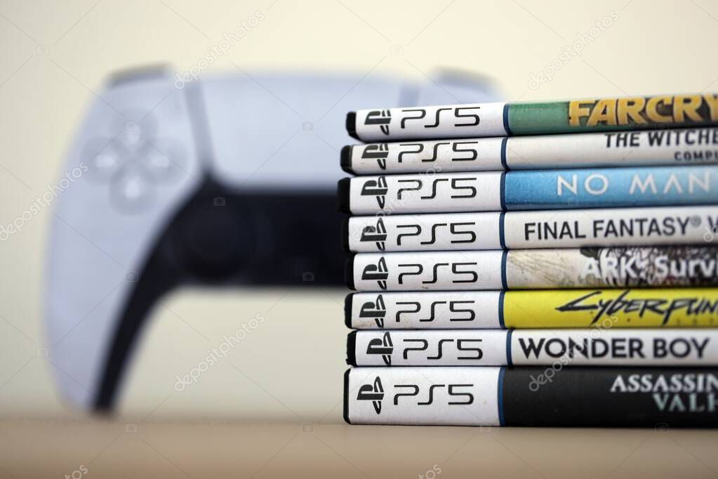 KYIV, UKRAINE - SEPTEMBER 17, 2025 Stack of PS5 videogame disc boxes and modern dualsense edge gamepad closer up