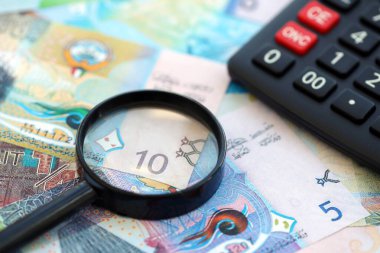 Kuveyt para birimi faturaları ve büyüteçle yakın çekim yapan hesap makinesi. Vergilendirme ve para sayımı kavramı