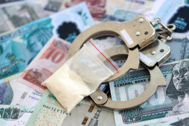 Mısır para birimi banknotları ve kelepçeli kokain paketi. Uyuşturucu suçları kavramı