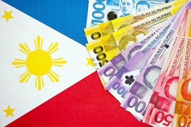 Filipinler Peso para birimi banknotları bayrağın üzerinde duruyor. İş ve yatırım kavramı