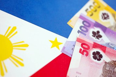 Filipinler Peso para birimi banknotları bayrağın üzerinde duruyor. İş ve yatırım kavramı