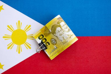 Filipinler Peso para birimi banknotları bayrağın üzerinde duruyor. İş ve yatırım kavramı