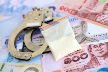 Tayland baht para birimi faturaları ve kelepçeli kokain paketi. Uyuşturucu suçları kavramı