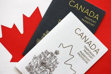 Canadian temporary and permanent passports lies on flag close up