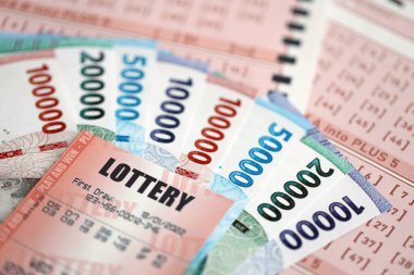 KYIV, UKRAINE - JANUARY 27, 2024 Red lottery ticket lies on pink gambling sheets with indonesian rupiah money bills. Lottery playing concept or gambling addiction in indonesia