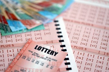 KYIV, UKRAINE - JANUARY 27, 2024 Red lottery ticket lies on pink gambling sheets with indonesian rupiah money bills. Lottery playing concept or gambling addiction in indonesia