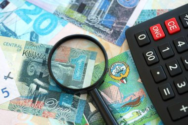 Kuveyt para birimi faturaları ve büyüteçle yakın çekim yapan hesap makinesi. Vergilendirme ve para sayımı kavramı