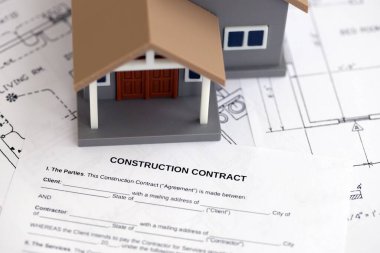 KYIV, UKRAINE - OCTOBER 3, 2025 Construction contract and toy house on white blueprints for construction close up