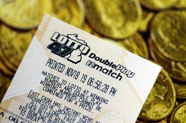 KYIV, UKRAINE - 22 Ekim 2025 Lotto 47 piyango bileti altın sikkelerin üzerinde yatıyor.