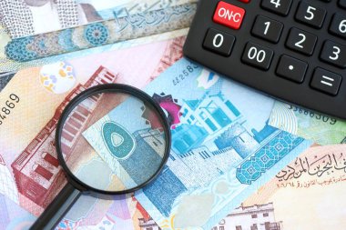Bahreyn dinar para birimi faturaları ve yakınlaştırıcı bardaklı hesap makinesi. Vergilendirme ve para sayımı kavramı