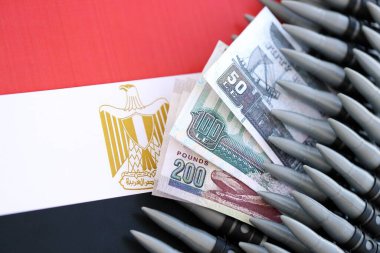 Mısır para birimi banknotları ve bayraklar üzerinde tüfek mermileri. Savaş ve silah satışı kavramı