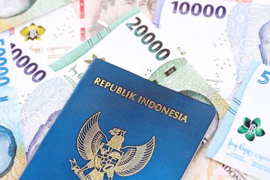 KYIV, UKRAINE - JANUARY 27, 2024 Indonesia passport and many indonesian rupiah currency money bills close up