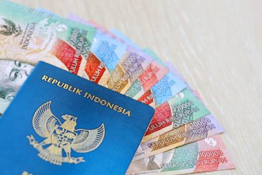 KYIV, UKRAINE - JANUARY 27, 2024 Indonesia passport and many indonesian rupiah currency money bills close up