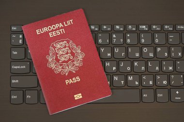 Estonya pasaportu siyah dizüstü bilgisayarın klavye düğmelerinin üzerinde. Avrupa konseptinde teknoloji ve kontrol