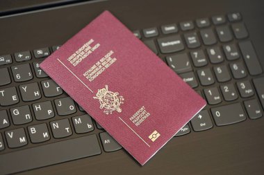 Belçika pasaportu siyah dizüstü bilgisayarın klavye düğmelerinin üzerinde. Avrupa konseptinde teknoloji ve kontrol