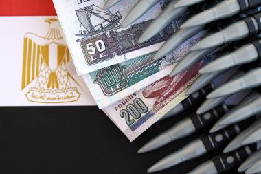 Mısır para birimi banknotları ve bayraklar üzerinde tüfek mermileri. Savaş ve silah satışı kavramı